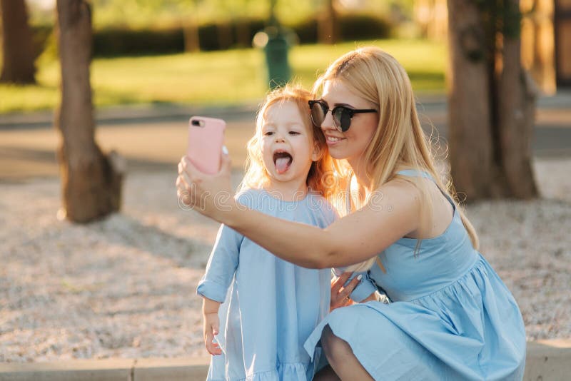 Het mamma en haar weinig dochter maken selfie in het park stock fotografie Het mamma en haar weinig dochter maken selfie in het park stock fotografie