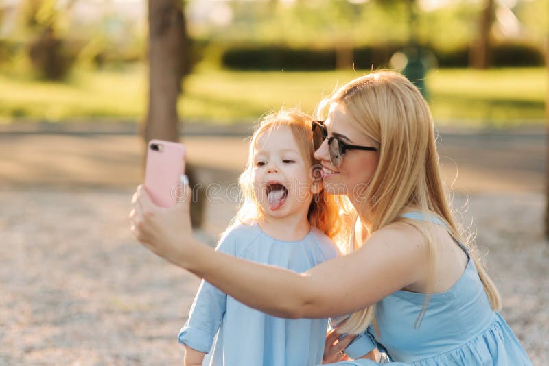 Het mamma en haar weinig dochter maken selfie in het park royalty-vrije stock foto Het mamma en haar weinig dochter maken selfie in het park royalty-vrije stock foto