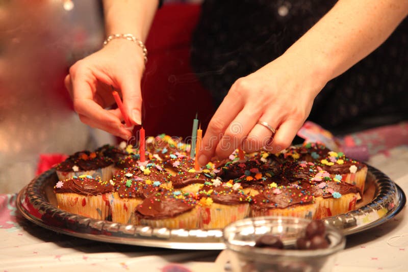 Het mamma verwijdert verjaardagskaarsen uit een partijdienblad van cupcakes stock afbeeldingen Het mamma verwijdert verjaardagskaarsen uit een partijdienblad van cupcakes stock afbeeldingen