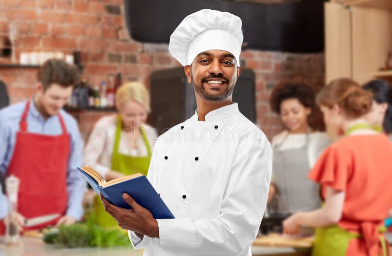 Het mannelijke Indische kookboek van de chef-koklezing bij het koken van klasse royalty-vrije stock afbeelding Het mannelijke Indische kookboek van de chef-koklezing bij het koken van klasse royalty-vrije stock afbeelding