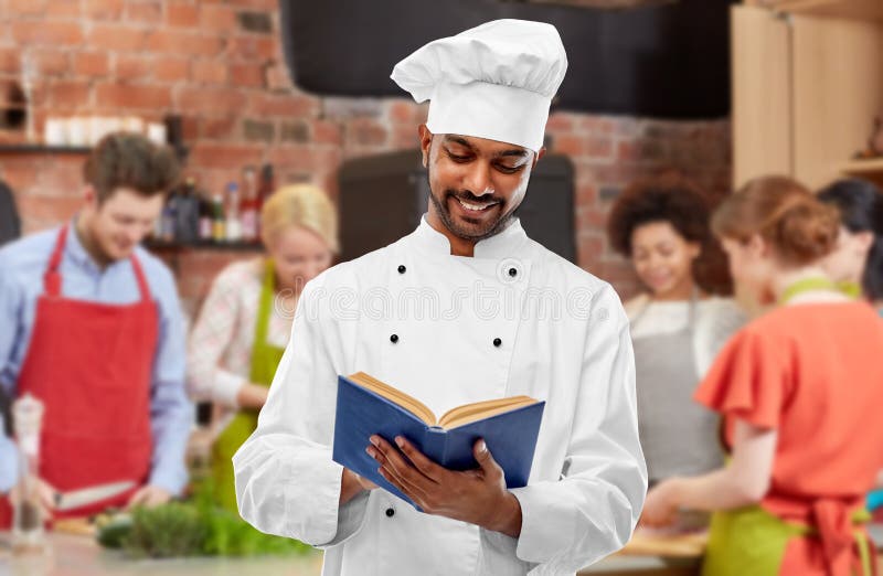 Het mannelijke Indische kookboek van de chef-koklezing bij het koken van klasse stock afbeeldingen Het mannelijke Indische kookboek van de chef-koklezing bij het koken van klasse stock afbeeldingen