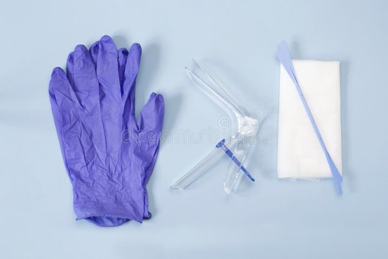 The medical plastic tool for holding open the vagina during medical investigation. An overhead photo of the vaginal speculum, white napkin, medicine gloves and spatula. Feminine woman health diagnosis. The medical plastic tool for holding open the vagina during medical investigation. An overhead photo of the vaginal speculum, white napkin, medicine gloves and spatula. Feminine woman health diagnosis