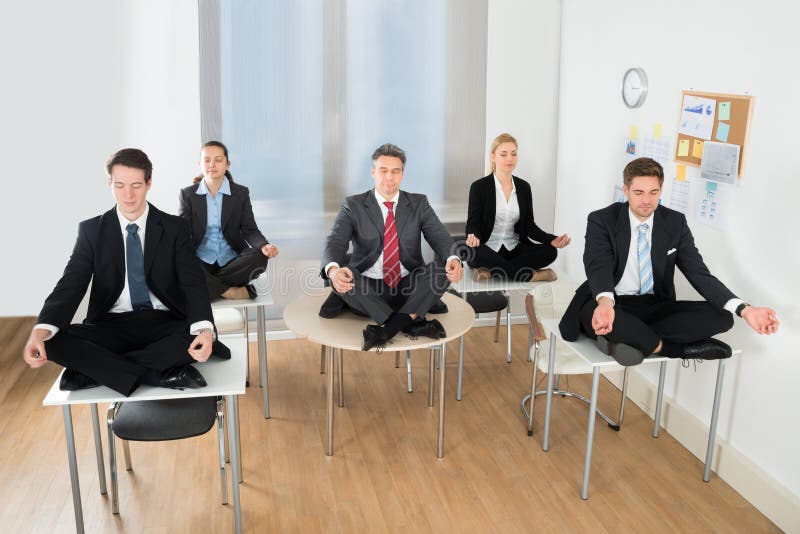 Het mediteren van zakenlui die op bureau zitten