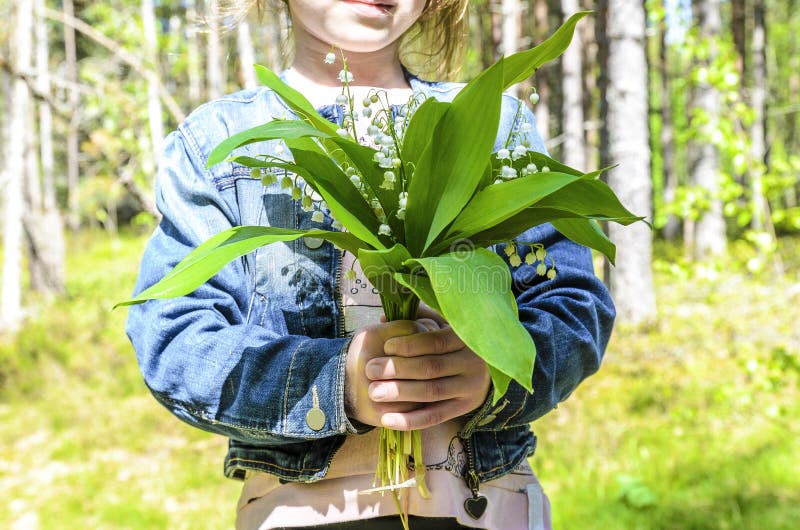 Het meisje bevindt zich in een groen bos en houdt een boeket van mooie bloemenlelietje-van-dalen stock foto's Het meisje bevindt zich in een groen bos en houdt een boeket van mooie bloemenlelietje-van-dalen stock foto's