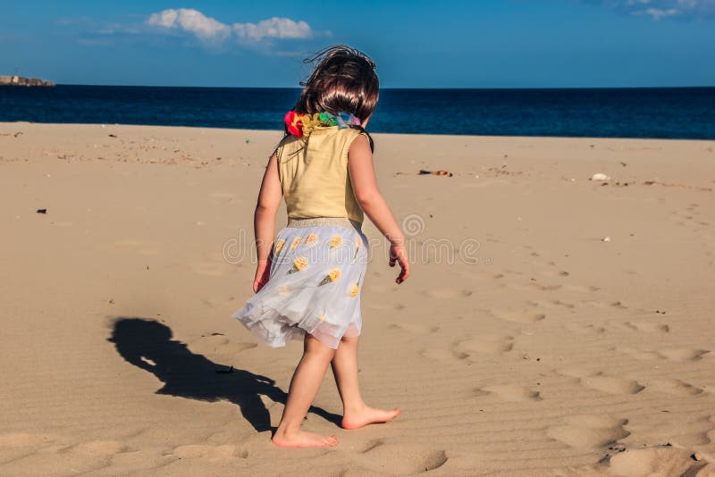 Het meisje bij strand, de zomer kleedde de gangen van het kindmeisje op zand voor shells royalty-vrije stock afbeelding Het meisje bij strand, de zomer kleedde de gangen van het kindmeisje op zand voor shells royalty-vrije stock afbeelding