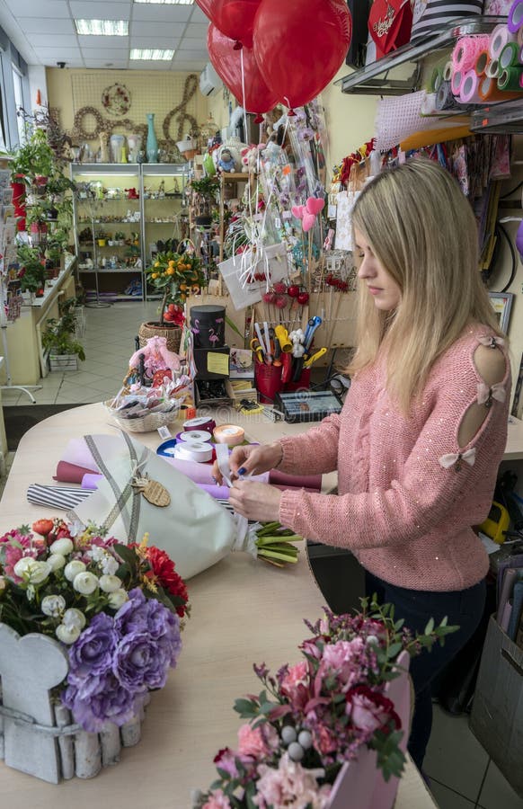 Het meisje, bloemist-ontwerper maakt een mooi, feestelijk boeket van bloemen in een bloemwinkel stock afbeelding Het meisje, bloemist-ontwerper maakt een mooi, feestelijk boeket van bloemen in een bloemwinkel stock afbeelding