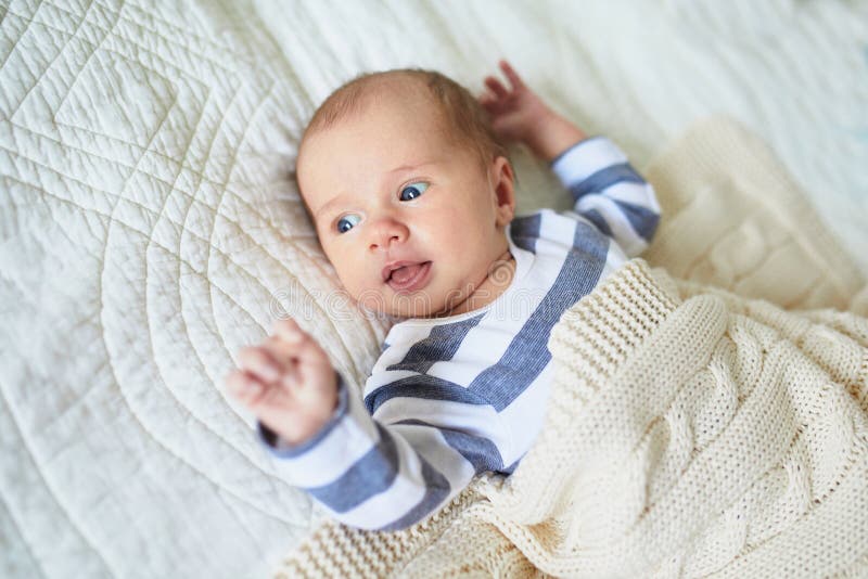Het meisje die van de één maandbaby onder gebreide deken liggen stock afbeelding Het meisje die van de één maandbaby onder gebreide deken liggen stock afbeelding