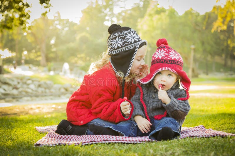 Het meisje fluistert een Geheim aan Babybroer Outdoors royalty-vrije stock foto Het meisje fluistert een Geheim aan Babybroer Outdoors royalty-vrije stock foto