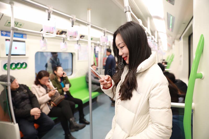 Het meisje gebruikt mobiele telefoon terwijl reis door metro, Vrouw gebruikend haar celtelefoon in Metro stock fotografie Het meisje gebruikt mobiele telefoon terwijl reis door metro, Vrouw gebruikend haar celtelefoon in Metro stock fotografie