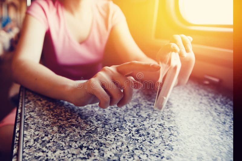 Het meisje in haar handen houdt een mobiele telefoon en port haar vinger in de reis door trein en trein in de auto stock afbeeldingen Het meisje in haar handen houdt een mobiele telefoon en port haar vinger in de reis door trein en trein in de auto stock afbeeldingen