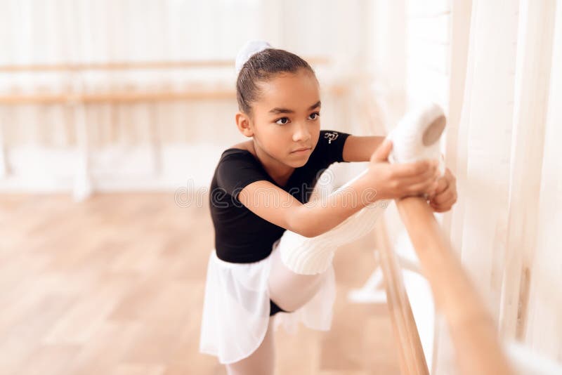 Het meisje leidt een rek van haar benen dichtbij het ballet op barr stock afbeelding Het meisje leidt een rek van haar benen dichtbij het ballet op barr stock afbeelding