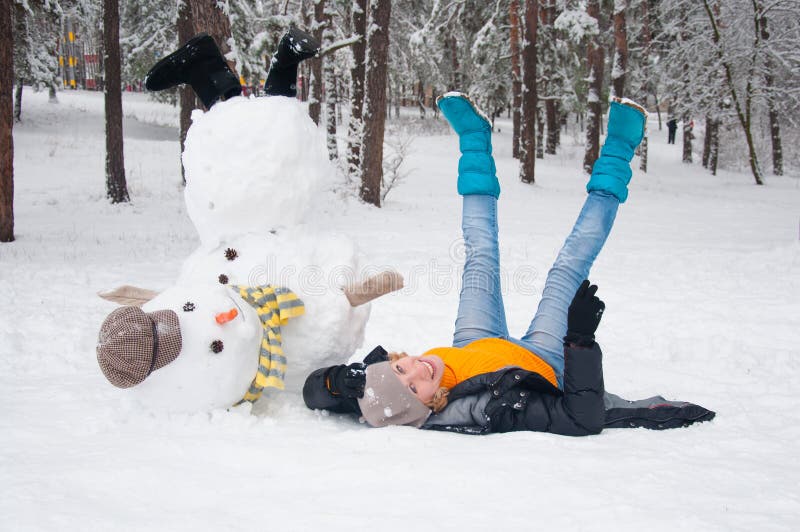 Amusing woman poses with the turned snowman. Amusing woman poses with the turned snowman