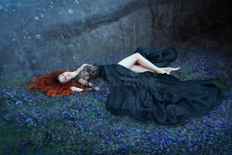 Het meisje met rood haar die op gras in donkere bos, zwarte koningin liggen verloor in slag, die dame in lange zwarte koninklijke