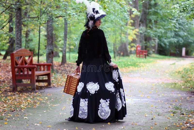 Het meisje in retro kledings 18de eeuw met valise in park royalty-vrije stock fotografie Het meisje in retro kledings 18de eeuw met valise in park royalty-vrije stock fotografie