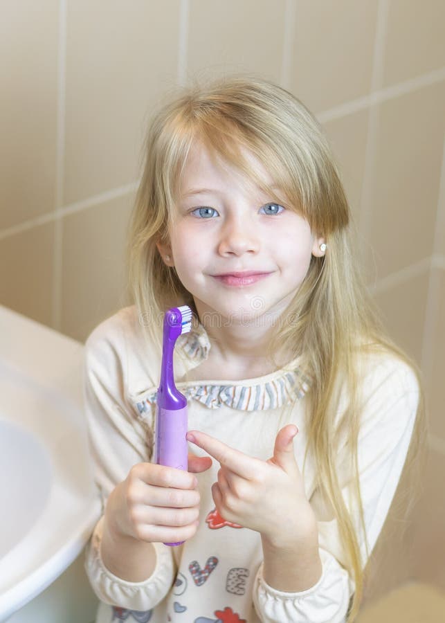 Het meisje toont de verrukkingen van een elektrische tandenborstel