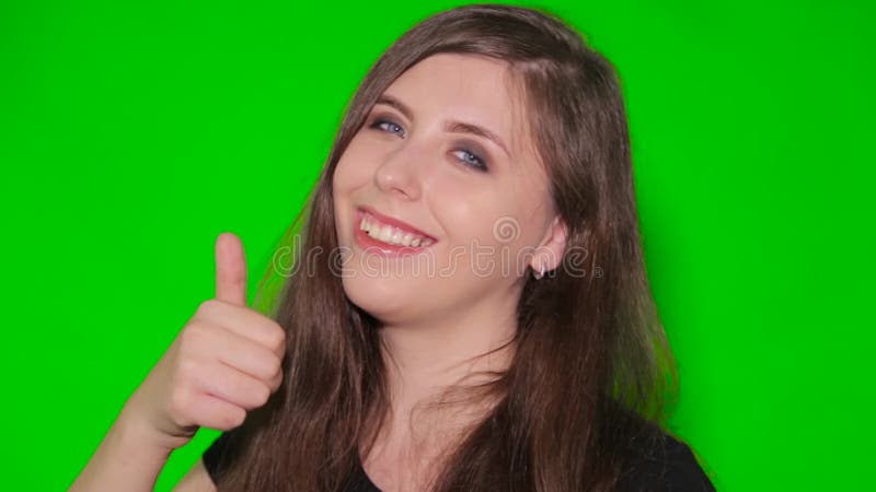 Het meisje toont een gebaarduim omhoog geïsoleerd op het groene scherm. een jonge glimlachende vrouw op chromakey achtergrond