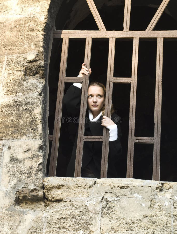 Het meisje van de tiener kijkt uit het gevangenisvenster stock fotografie Het meisje van de tiener kijkt uit het gevangenisvenster stock fotografie