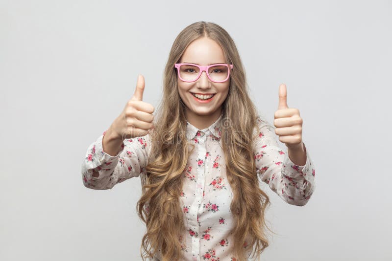 Het meisje van het gelukblonde in zonnebril, die duimen tonen, het kijken royalty-vrije stock afbeeldingen Het meisje van het gelukblonde in zonnebril, die duimen tonen, het kijken royalty-vrije stock afbeeldingen