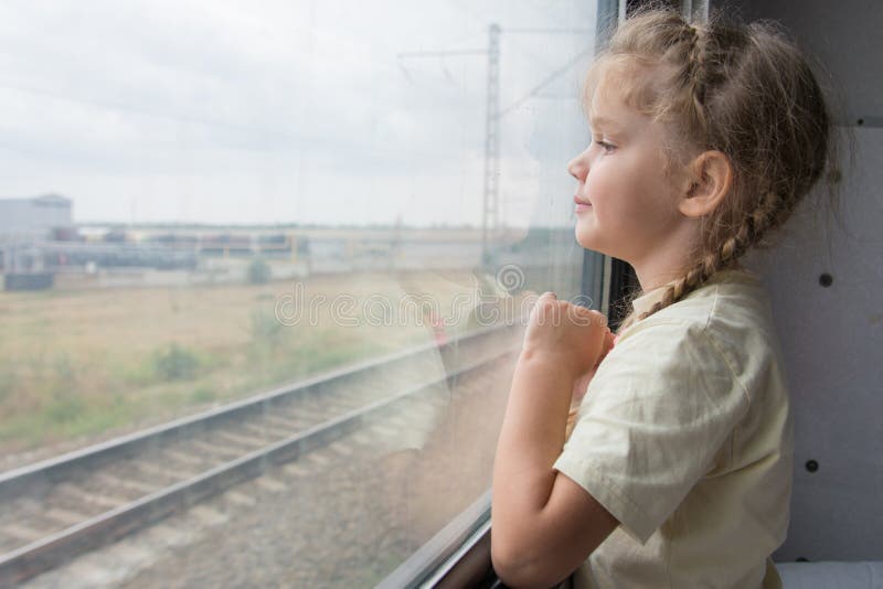 Het meisje van vier jaar kijkt uit het venster van de treinauto stock foto Het meisje van vier jaar kijkt uit het venster van de treinauto stock foto