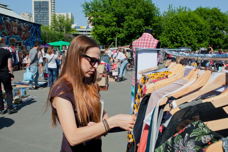 Het meisje wil kleding op de straatvlooienmarkt kopen royalty-vrije stock afbeeldingen Het meisje wil kleding op de straatvlooienmarkt kopen royalty-vrije stock afbeeldingen