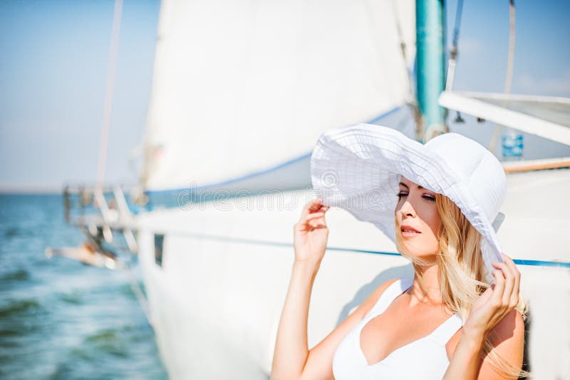 Het meisje in wit breed-brimmed hoed die dichtbij jacht varen royalty-vrije stock fotografie Het meisje in wit breed-brimmed hoed die dichtbij jacht varen royalty-vrije stock fotografie