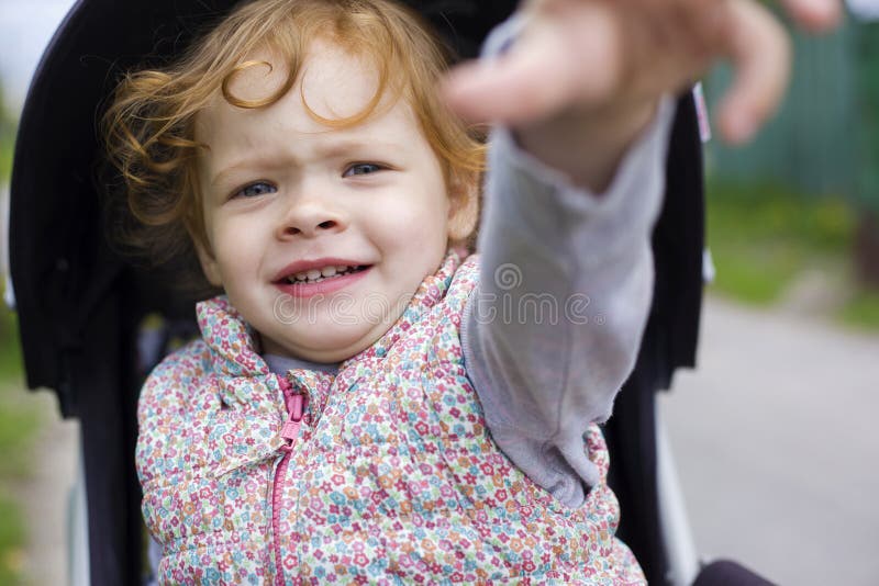 Het meisje is zenuwachtig in de wandelwagen stock fotografie Het meisje is zenuwachtig in de wandelwagen stock fotografie