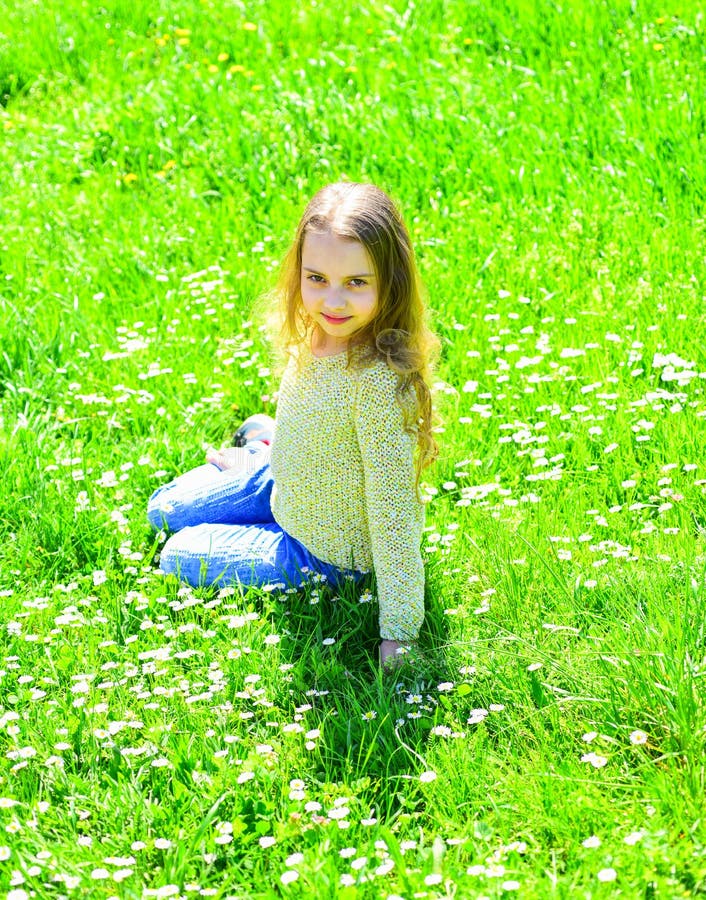 Het meisje zit op gras bij grassplot, groene achtergrond Het kind geniet de lente van zonnig weer terwijl het zitten bij weide ho royalty-vrije stock foto's Het meisje zit op gras bij grassplot, groene achtergrond Het kind geniet de lente van zonnig weer terwijl het zitten bij weide ho royalty-vrije stock foto's