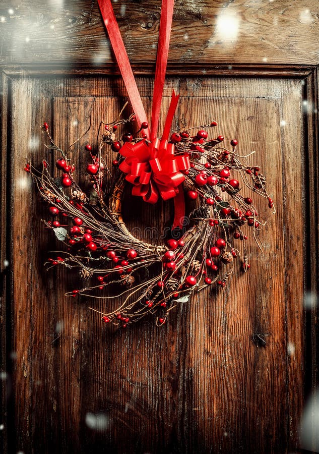 Het met de hand gemaakte Kerstmiskroon hangen op oude oude houten deur met rood lint en bessen met sneeuw royalty-vrije stock fotografie Het met de hand gemaakte Kerstmiskroon hangen op oude oude houten deur met rood lint en bessen met sneeuw royalty-vrije stock fotografie