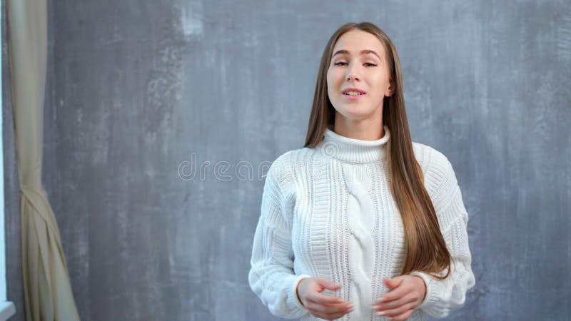 Het middel schoot portret van het mooie Europese sprekersvrouw spreken bij studio grijze achtergrond