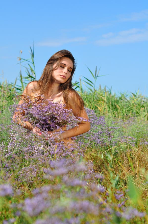 Het mooie die meisje is op het gebied met bloemen wordt behandeld stock afbeelding Het mooie die meisje is op het gebied met bloemen wordt behandeld stock afbeelding