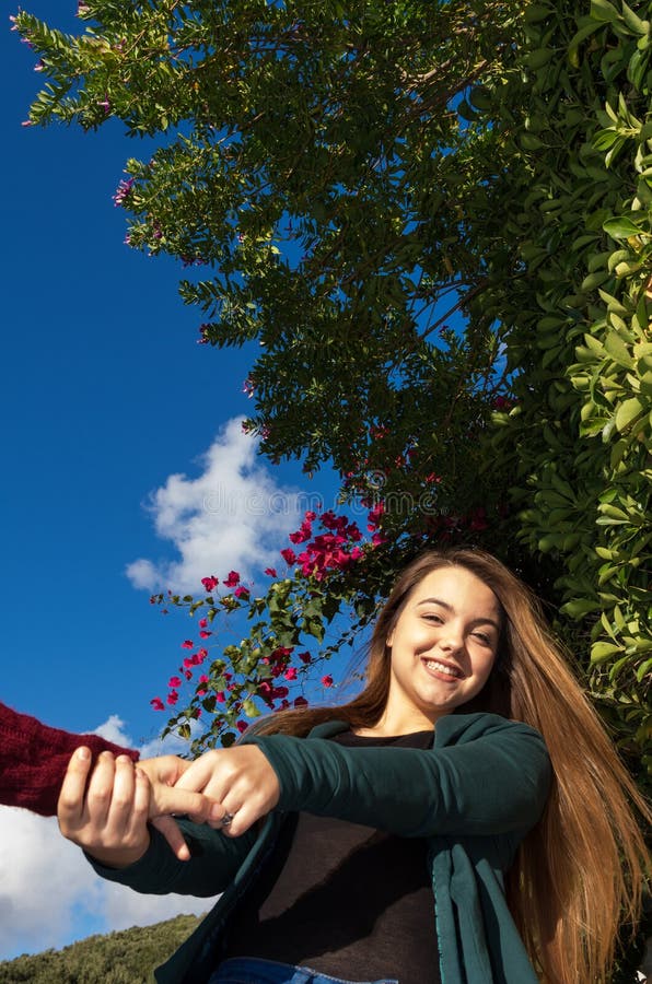 Het mooie en glimlachende jonge meisje houdt handen van een haar trekken en vriend die dansen stock foto's Het mooie en glimlachende jonge meisje houdt handen van een haar trekken en vriend die dansen stock foto's