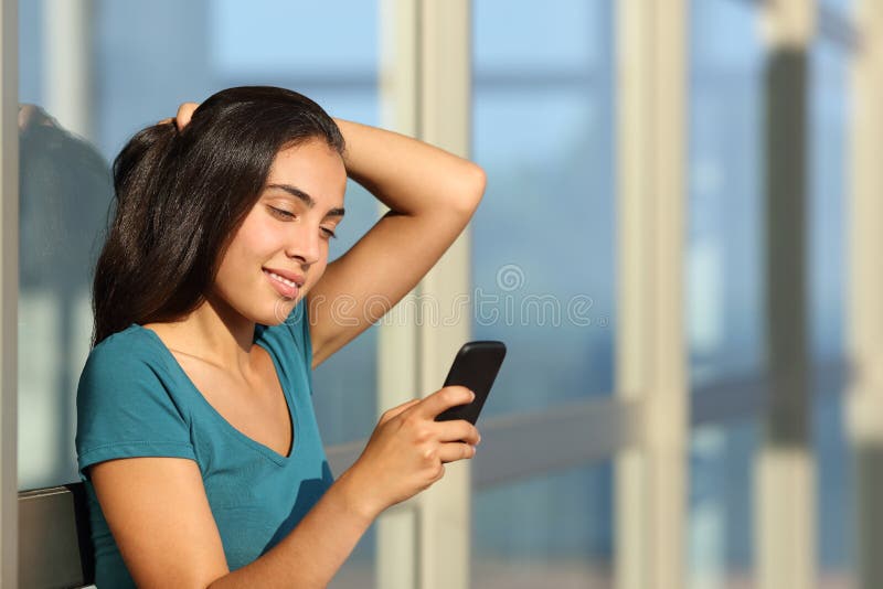 Het mooie gelukkige tienermeisje texting op een slimme telefoon openlucht royalty-vrije stock foto's Het mooie gelukkige tienermeisje texting op een slimme telefoon openlucht royalty-vrije stock foto's