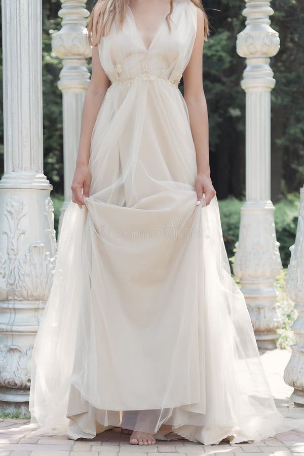Het mooie gevoelige bruid sexy meisje in een lichte beige huwelijkskleding loopt in de tuin heldere zonnige warme dag stock afbeelding Het mooie gevoelige bruid sexy meisje in een lichte beige huwelijkskleding loopt in de tuin heldere zonnige warme dag stock afbeelding