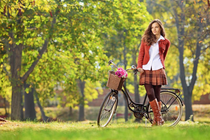Het mooie jonge vrouwelijke stellen in park met een fiets royalty-vrije stock foto's Het mooie jonge vrouwelijke stellen in park met een fiets royalty-vrije stock foto's