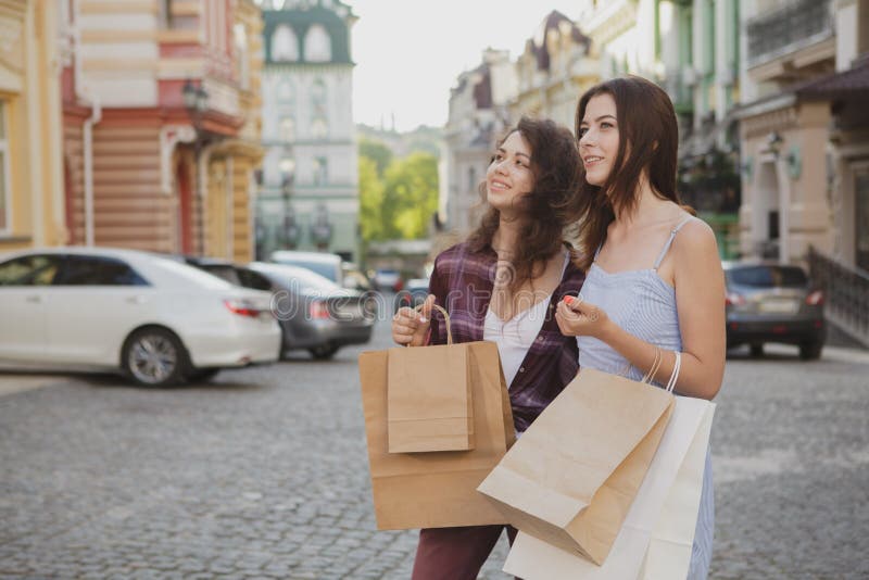 Het mooie jonge vrouwen genieten die stadsstraten samen na het winkelen lopen stock foto's Het mooie jonge vrouwen genieten die stadsstraten samen na het winkelen lopen stock foto's