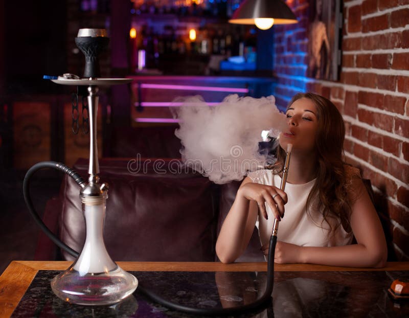 Het mooie meisje in een witte blouse rookt een waterpijp binnen de bar stock foto's Het mooie meisje in een witte blouse rookt een waterpijp binnen de bar stock foto's
