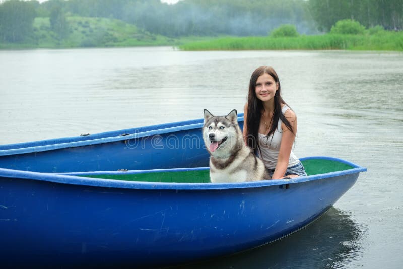 Het mooie meisje en een Schor hond in de boot stock foto's Het mooie meisje en een Schor hond in de boot stock foto's
