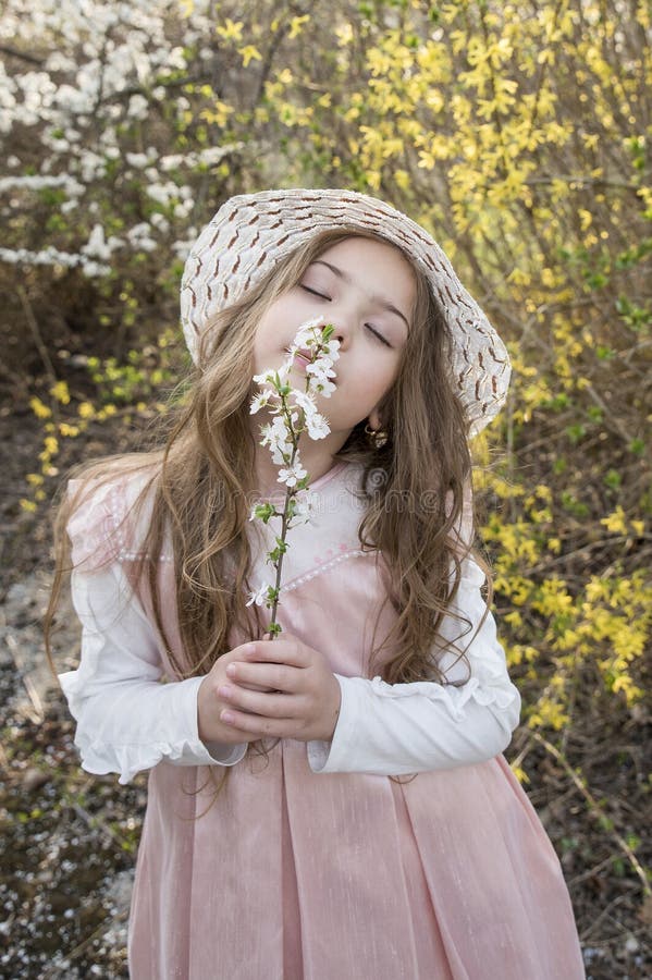 Het mooie meisje met hoed in aard ruikt bloemen royalty-vrije stock afbeelding Het mooie meisje met hoed in aard ruikt bloemen royalty-vrije stock afbeelding