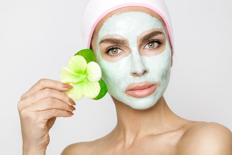 Beautiful blonde woman model with a green facial mask, beauty spa whit fragrant beautiful flower. Beautiful blonde woman model with a green facial mask, beauty spa whit fragrant beautiful flower