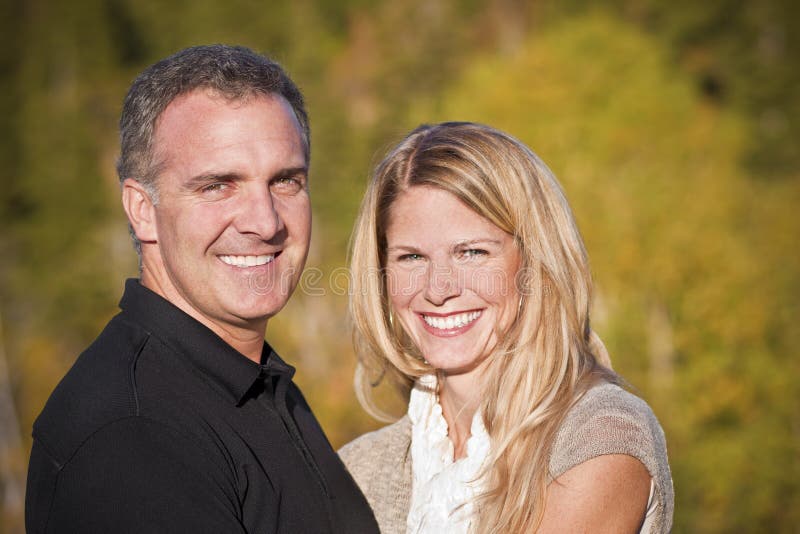 A Beautiful Middle-Aged Couple portrait outdoors with fall colors in the background. A Beautiful Middle-Aged Couple portrait outdoors with fall colors in the background