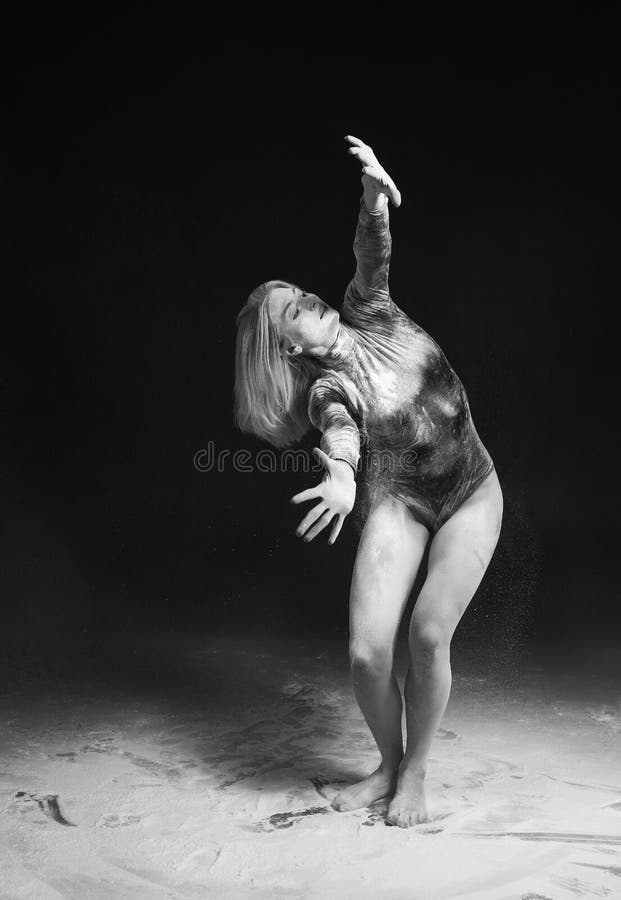 Het mooie slanke meisje die gymnastiek- die bodysuit dragen met witte het stofsprongen van de poedertalk wordt behandeld danst op stock foto's Het mooie slanke meisje die gymnastiek- die bodysuit dragen met witte het stofsprongen van de poedertalk wordt behandeld danst op stock foto's