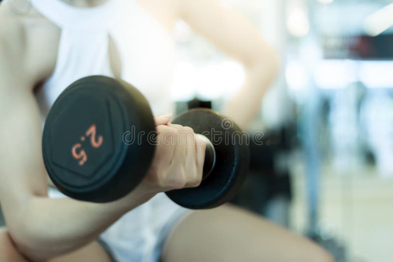 Het mooie sportmeisje heft domoor voor het bereiken van haar bicepsen op royalty-vrije stock fotografie Het mooie sportmeisje heft domoor voor het bereiken van haar bicepsen op royalty-vrije stock fotografie