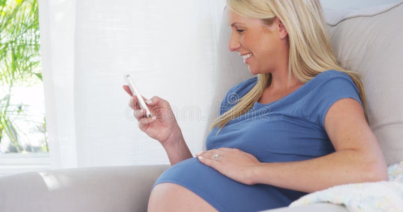 Het mooie zwangere vrouw texting op smartphone stock foto's Het mooie zwangere vrouw texting op smartphone stock foto's
