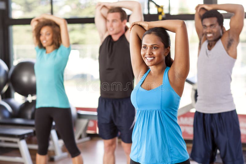 Multi-ethnic group stretching in a gym before their exercise class. Multi-ethnic group stretching in a gym before their exercise class