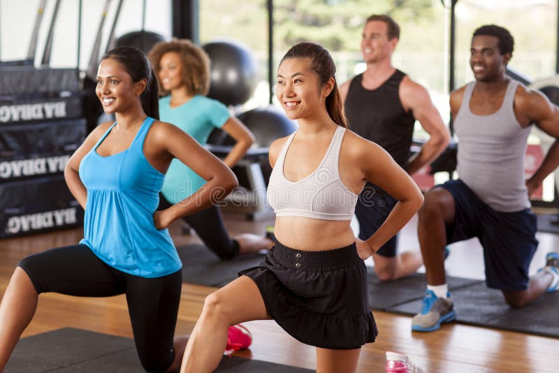 Multi-ethnic group stretching in a gym before their exercise class. Multi-ethnic group stretching in a gym before their exercise class