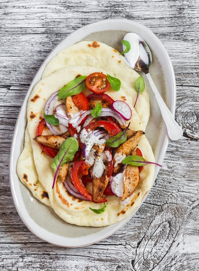 Het Naanbrood met kippengroente beweegt gebraden gerecht en yoghurtsaus op plaat op rustieke lichte houten achtergrond stock foto Het Naanbrood met kippengroente beweegt gebraden gerecht en yoghurtsaus op plaat op rustieke lichte houten achtergrond stock foto