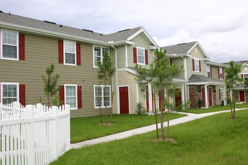 New condominium village consisting of attractive condos with red shutters and doors and trimmed in white, sidewalks and beginning of landscaping. New condominium village consisting of attractive condos with red shutters and doors and trimmed in white, sidewalks and beginning of landscaping