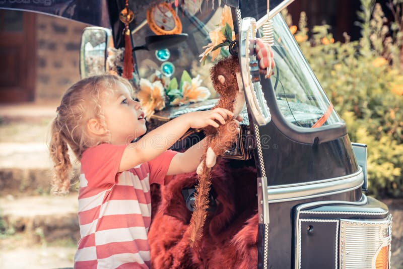 Het nieuwsgierige meisje van de kindreiziger onderzoekt speelgoed op tuk tuk motor tijdens van het conceptenkinderen van reisazië royalty-vrije stock foto's Het nieuwsgierige meisje van de kindreiziger onderzoekt speelgoed op tuk tuk motor tijdens van het conceptenkinderen van reisazië royalty-vrije stock foto's