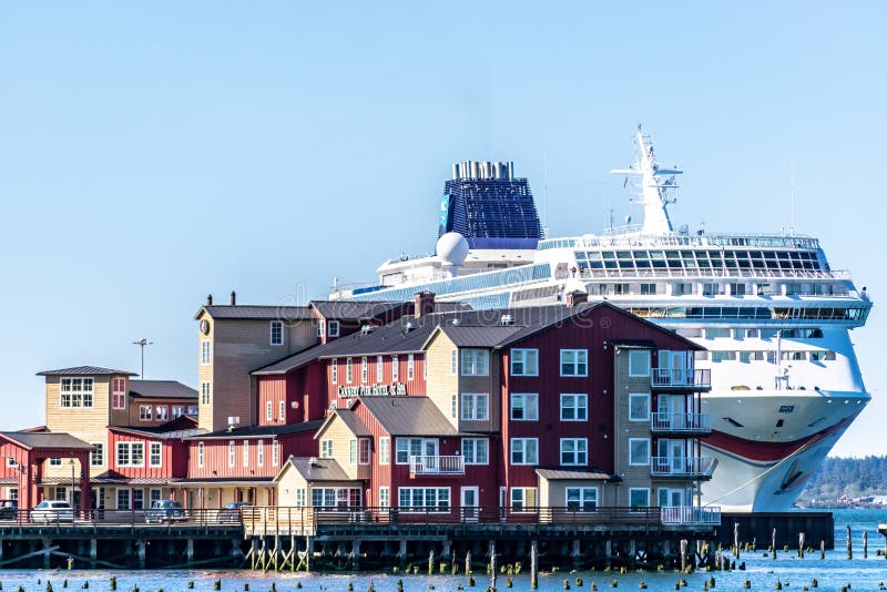 Het Noorse NCL-schip van de Zoncruise dokte in Astoria van de binnenstad achter de Conservenfabriek Pier Hotel en Kuuroord op de stock fotografie Het Noorse NCL-schip van de Zoncruise dokte in Astoria van de binnenstad achter de Conservenfabriek Pier Hotel en Kuuroord op de stock fotografie