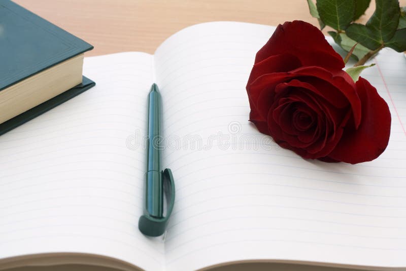 A personal diary is open and ready for the day's entry. A single red rose lays on top of the diary. A personal diary is open and ready for the day's entry. A single red rose lays on top of the diary...